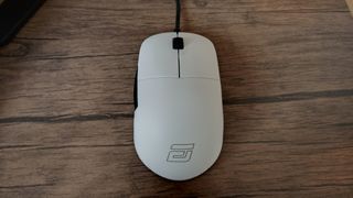 A white Endgame Gear XM1r gaming mouse on a wooden table