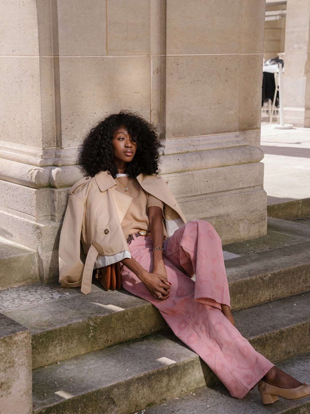 Influencer Emmanuelle Koffi wearing a cropped trench jacket, printed jeans and heeled ballet pumps.