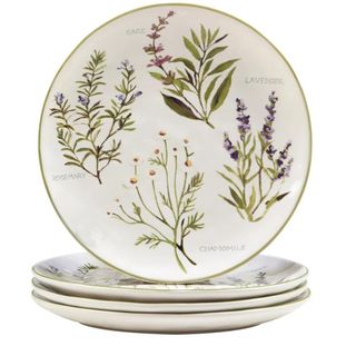 A stack of white decorative plates with herbs painted on