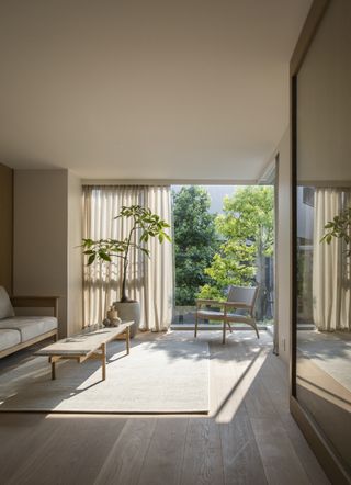 A neutral Japandi interior with a view looking out onto a terrace with greenery