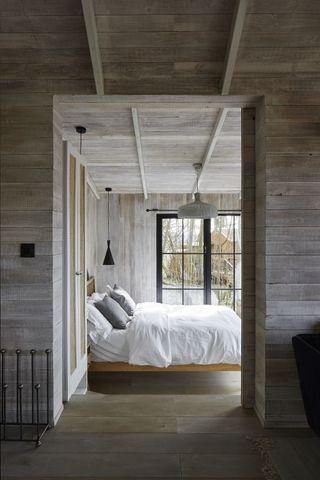 rustic timber cladding on ceiling of bedroom with large window