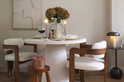 A white table with boucle armchairs dressed for Christmas