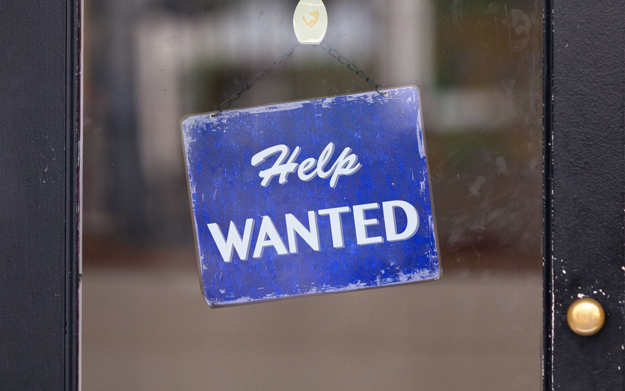 Close-up on a blue help wanted sign.