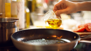Someone pouring olive oil into a pan