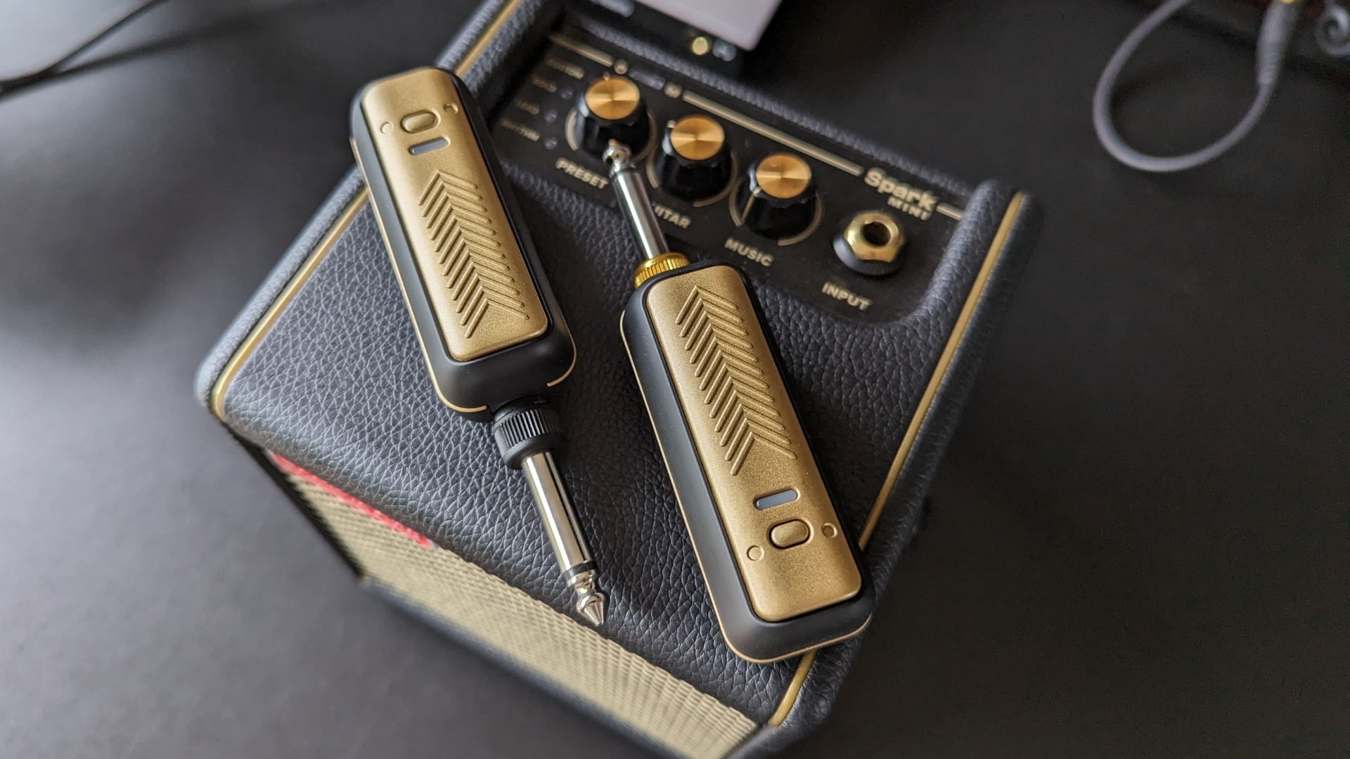 A Positive Grid Spark Link transmitter and receiver on top of a Positive Grid Spark Mini practice amp
