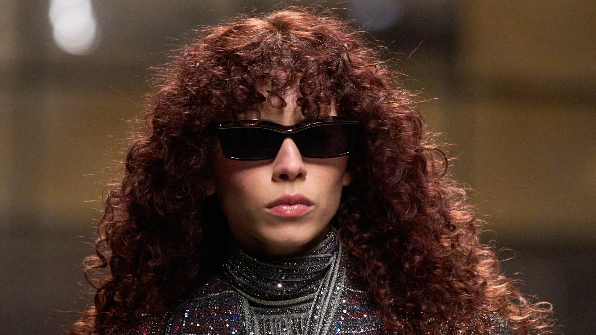 Model with curly red hair wearing sunglasses