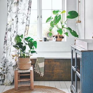white bathroom with brown bath, shower curtain and plants everywhere