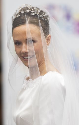 a close up of Olivia Henson at her wedding in a floral tiara and dress