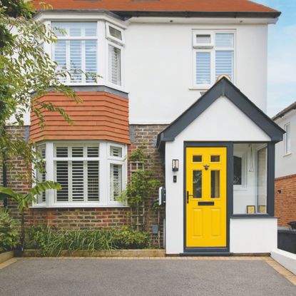 White render house with brick and a yellow front door