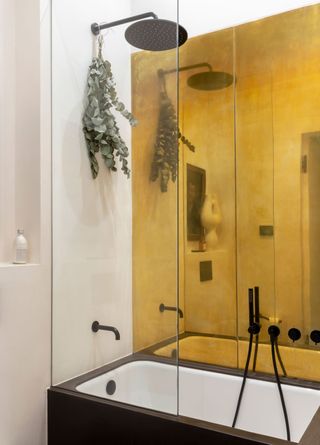 a bathroom in an apartment with a brass wall covering