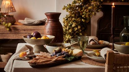 A fall dining table laden with seasonal food in stoneware dishes.