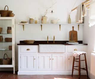 cottage kitchen idea with white shaker units, butler sink and wooden shelving above