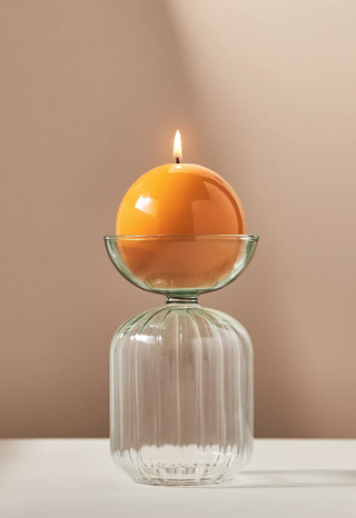 glass ornament holding a lit candle in the top half-globe section