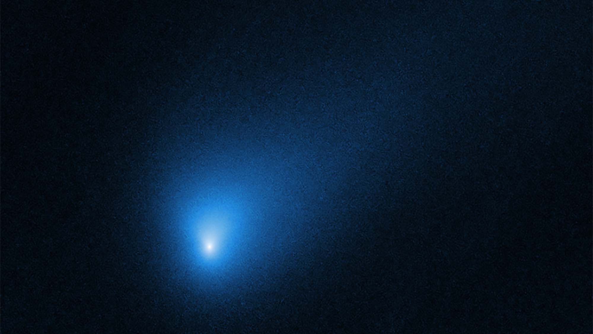 Rogue comet 2I/Borisov seen in a faint blue haze with a bright blue nucleus against the black backdrop of space