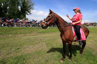 The pack rides near a woman riding a horse during the 15th stage of the Giro dItalia 2021 a 147km cycling race between Grado and Gorizia on May 23 2021 Photo by Luca Bettini AFP Photo by LUCA BETTINIAFP via Getty Images