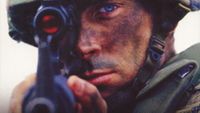 A soldier aims down the sight of an assault rifle.