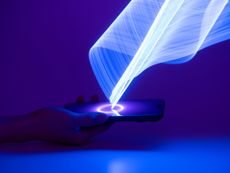 a hand holding a smartphone with a white light emanating from a circle in the middle of the screen