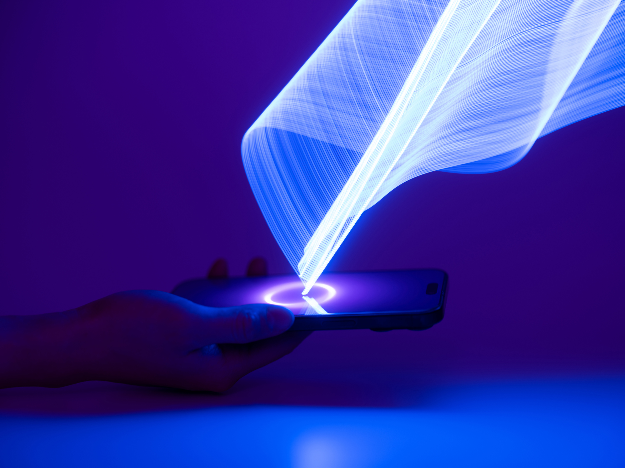 a hand holding a smartphone with a white light emanating from a circle in the middle of the screen 