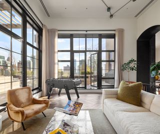 Trevor Noah's Penthouse – corner windows with city views, a games table and comfortable armchair