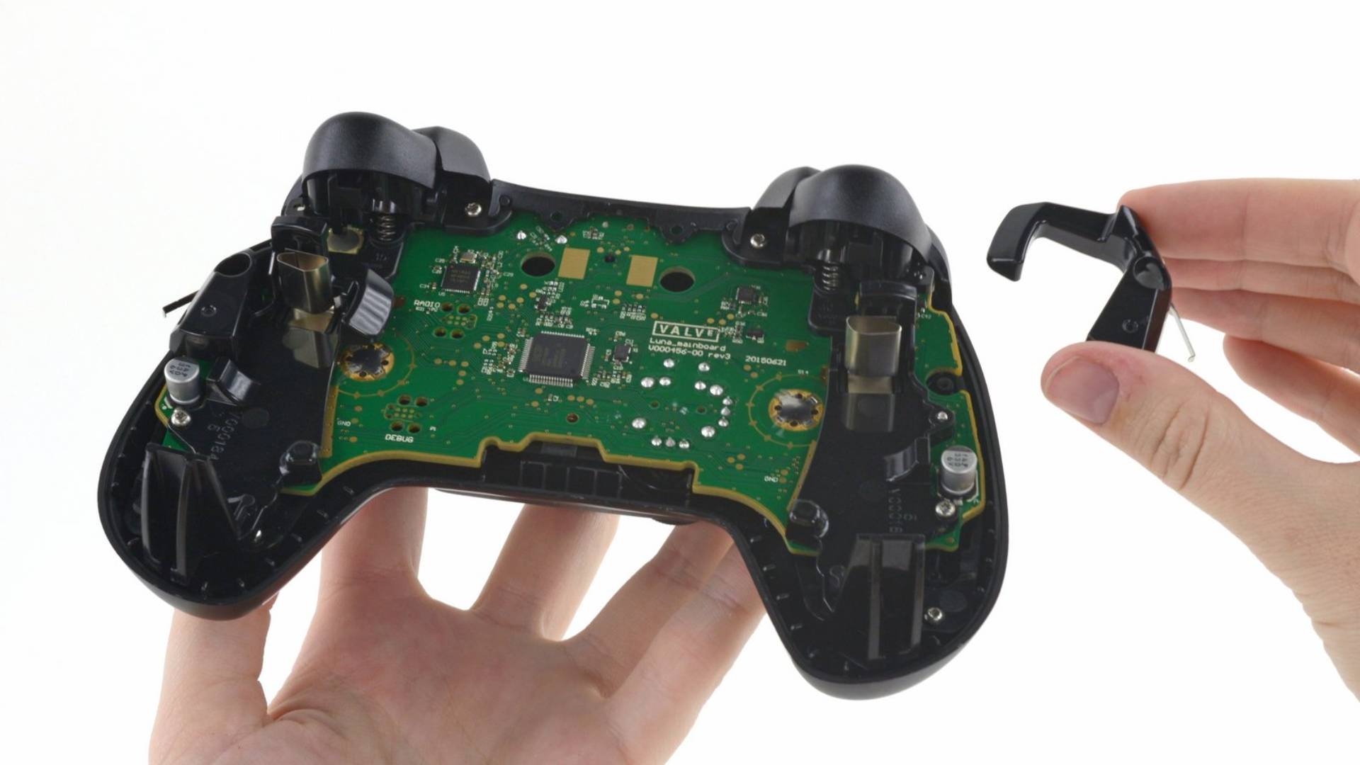 Steam Controller with back removed in one hand and another holding trigger on right.