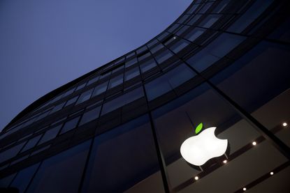 The Apple logo glows on the side of a building