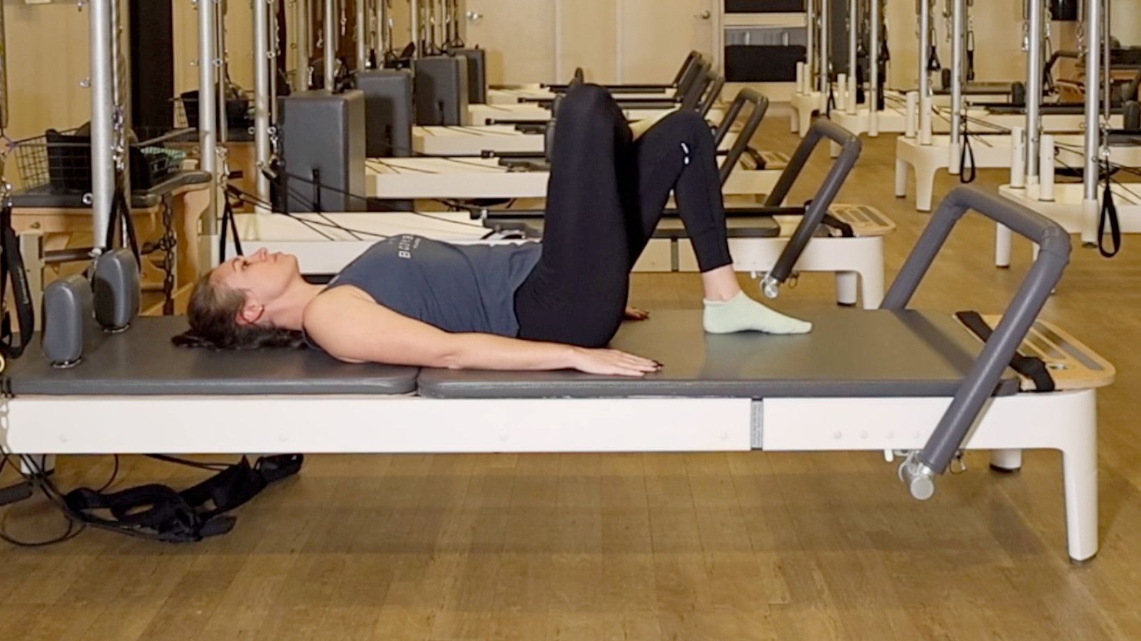 Woman demonstrating a Pilates exercise on the carriage of a Pilates reformer machine