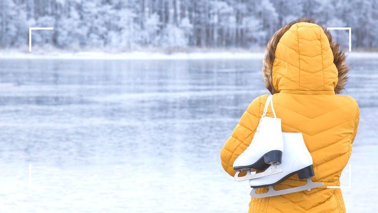 woman in a yellow coat holding ice skates