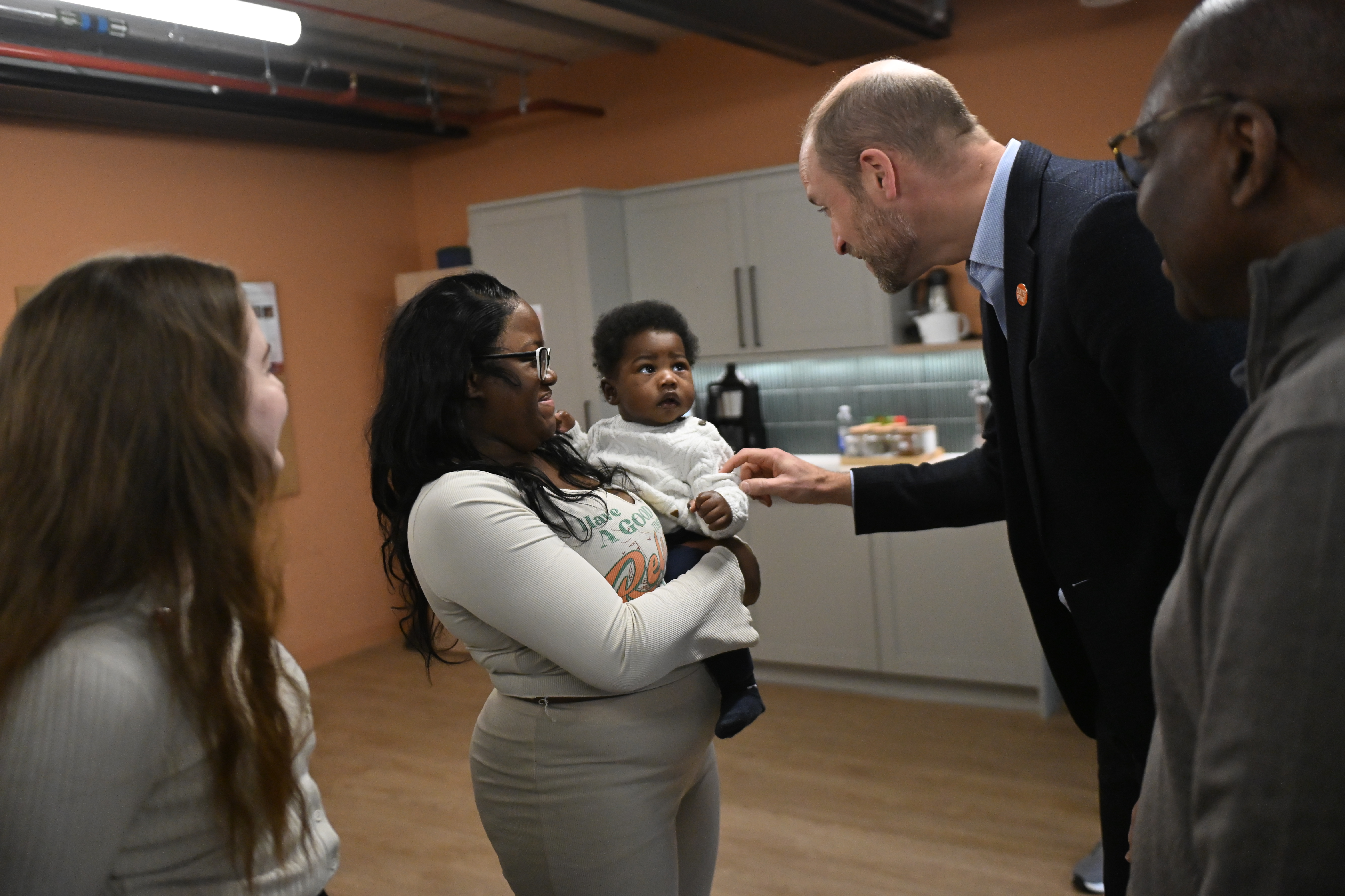 Prince William talking to a baby and two women at Centrepoint