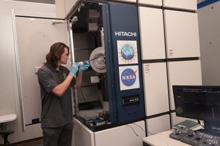 a scientist places a tray into a large locker-like machine