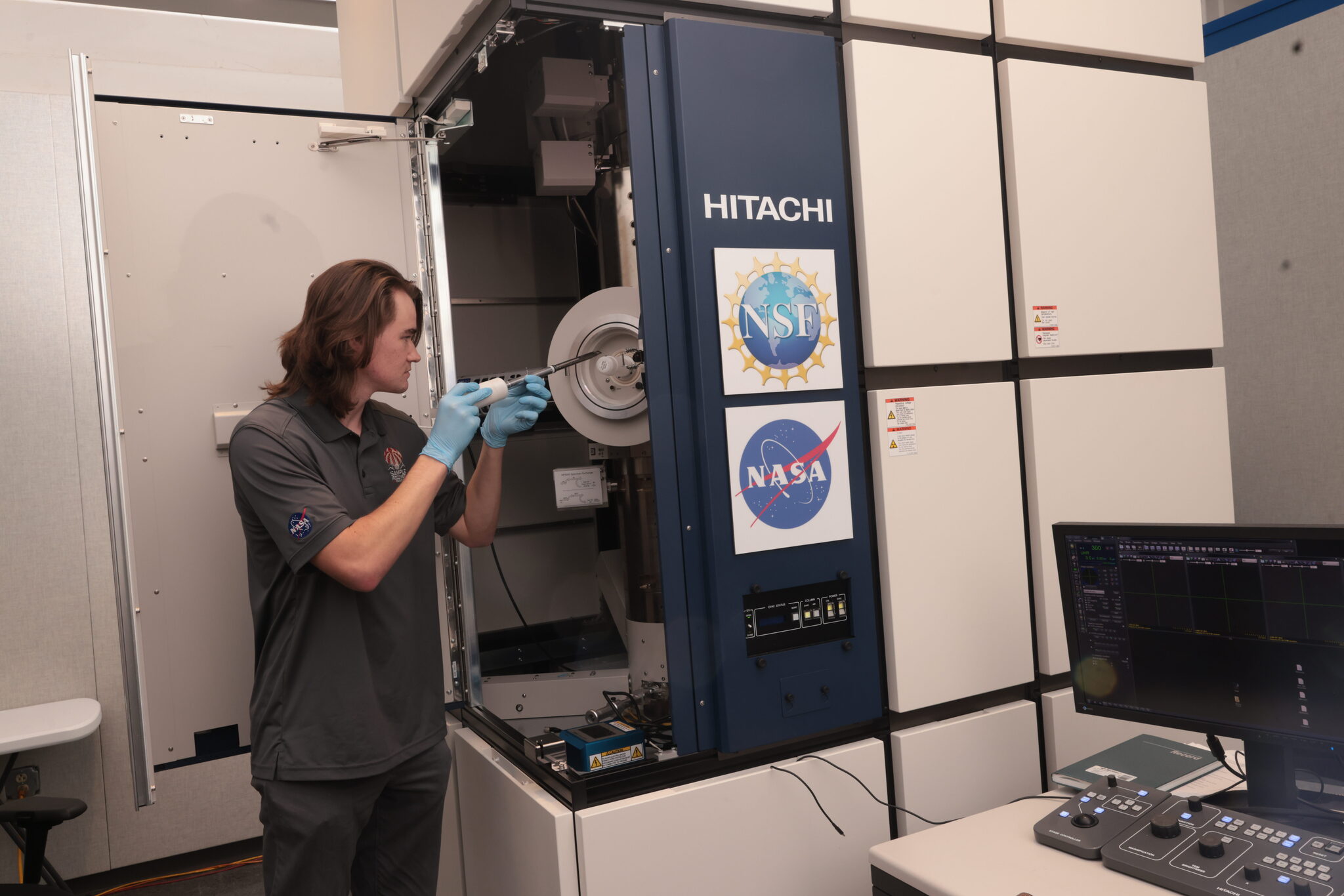 A scientist places a plate in a large locker-like machine