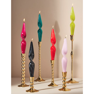 assortment of colorful twisted candles in gold holders
