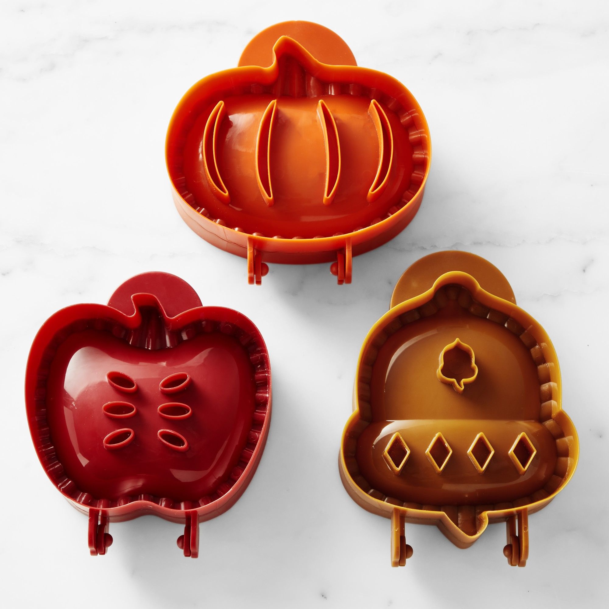 Three hand pie molds in the shape of an apple, acorn, and pumpkin.