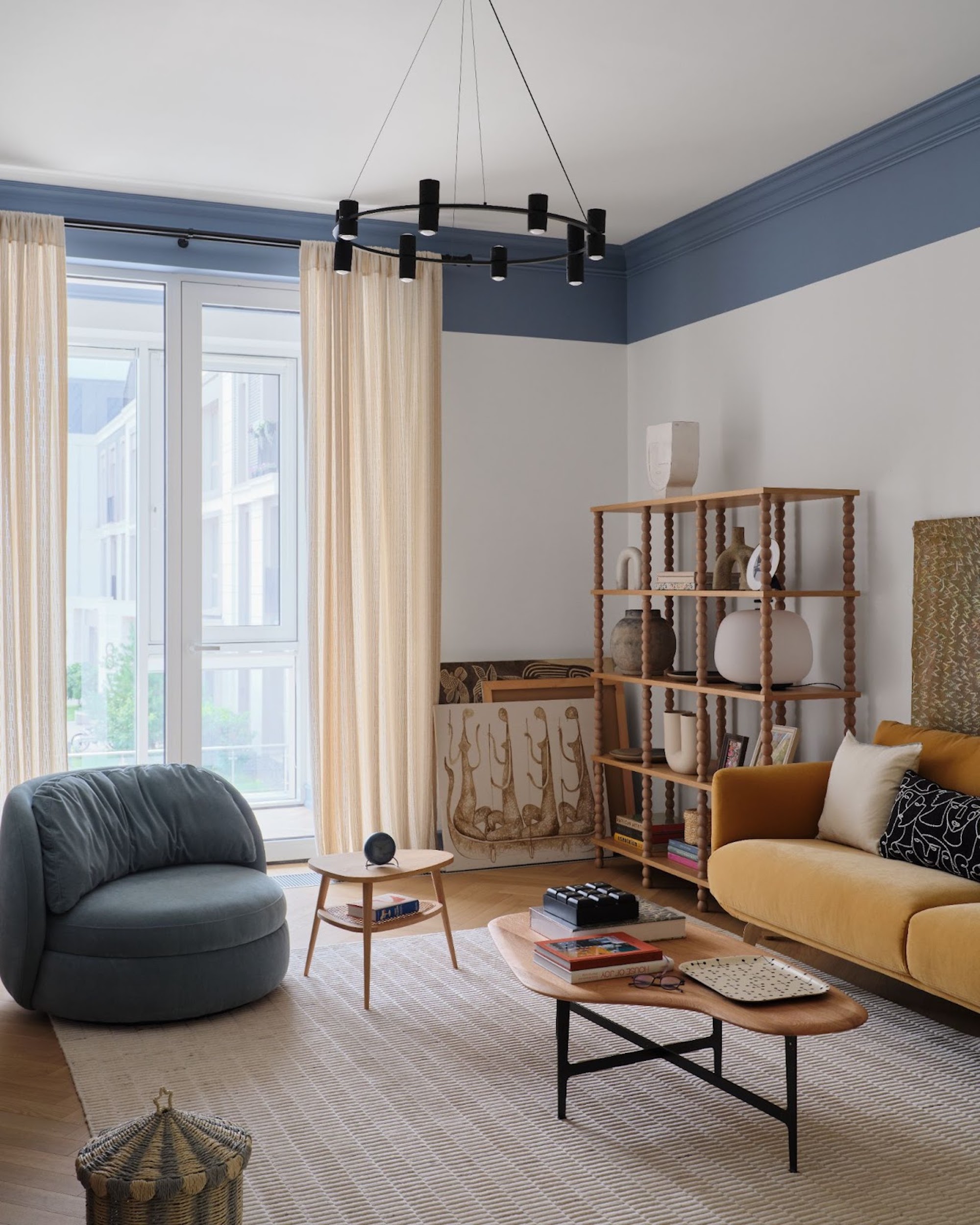 View of the living space through to the floor to ceiling window, with the blue arm chair to the left and the coffee table in the centre of the space.