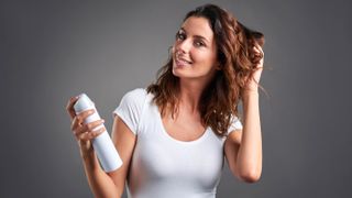 A woman applying hairspray to her hair