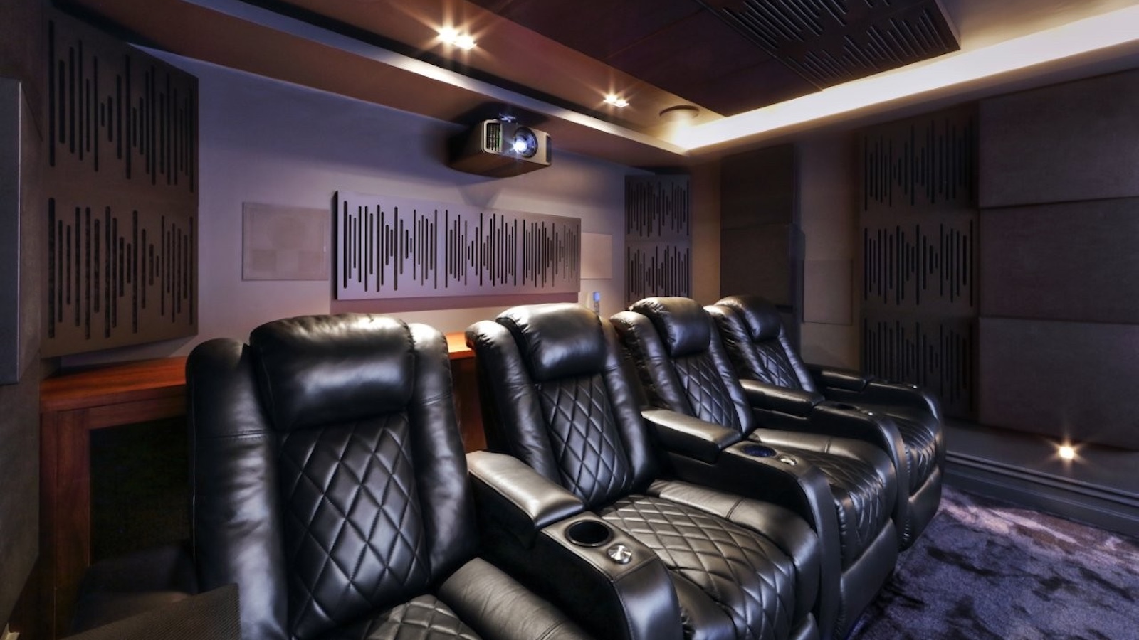 A photo of a custom-installed home cinema room featuring a 4K projector, theatre seating and clever acoustic treatment