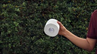 Man holding white toilet roll in the garden