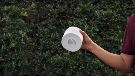 Man holding white toilet roll in the garden