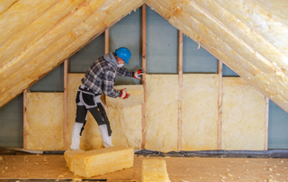Man installing insulation in a loft