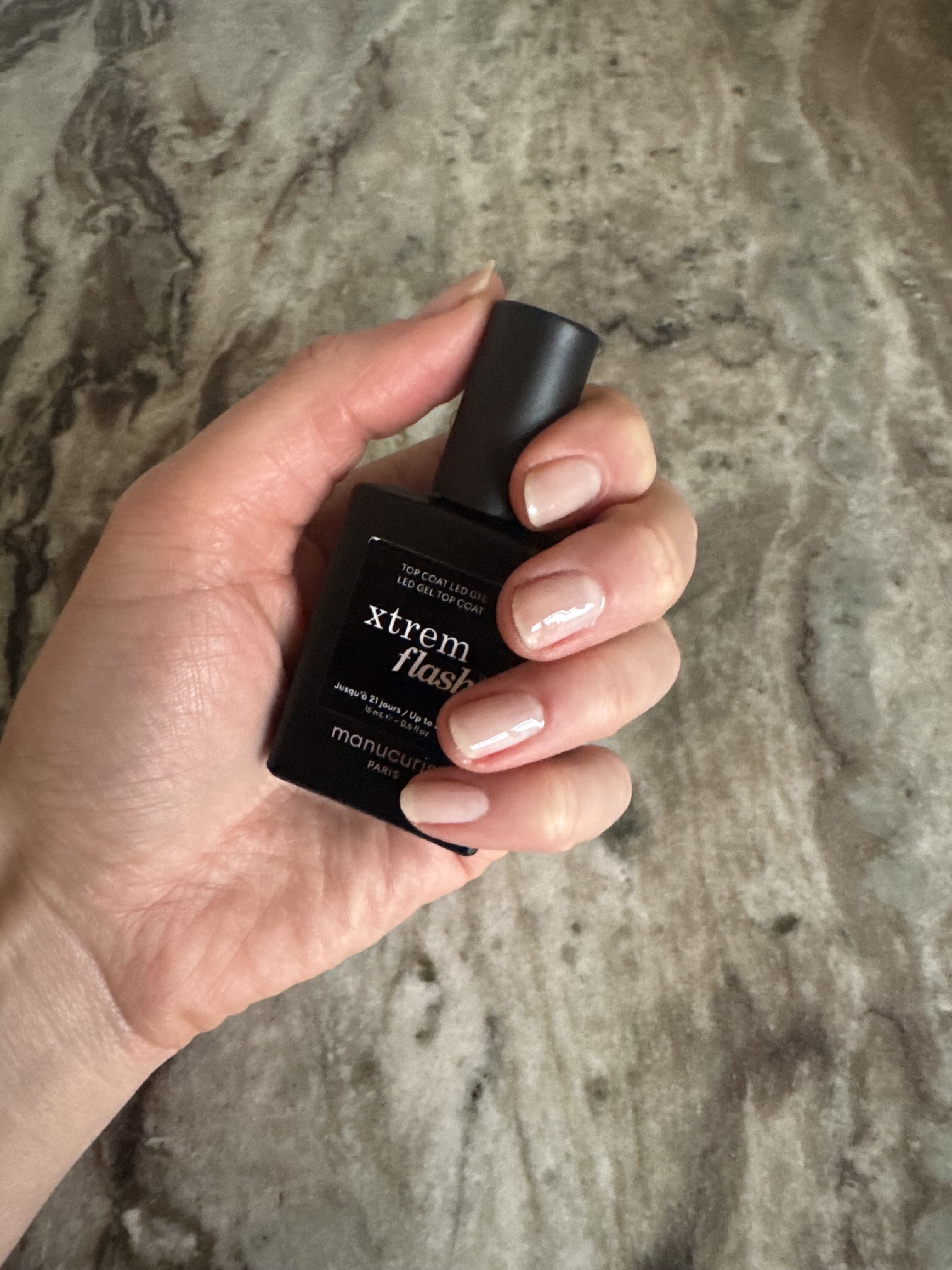 Eleanor holding the Manucurist Xtrem Flash Top Coat and wearing it on her nails with Pale Rose Green Flash nail polish