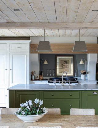 Country kitchen with green painted island and wooden beams