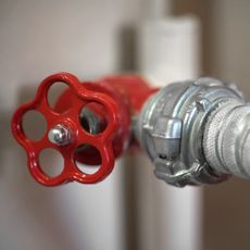 Red stopcock with circular head fixed to silver water pipe
