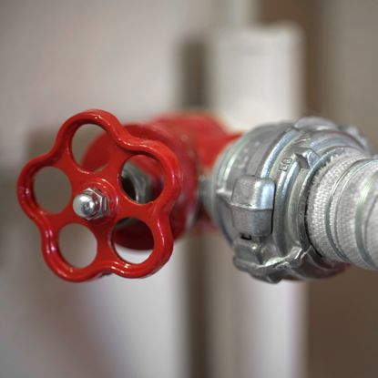 Red stopcock with circular head fixed to silver water pipe