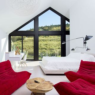 Room with white bed and maroon sofa