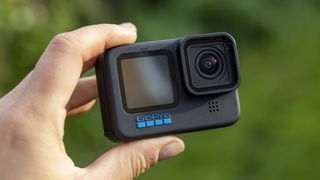 A GoPro Hero 12 Black being handheld against a green backdrop
