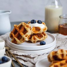 Waffles on a white plate with blueberries and cream
