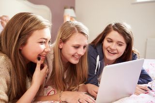 Three teen girls look at a computer together.