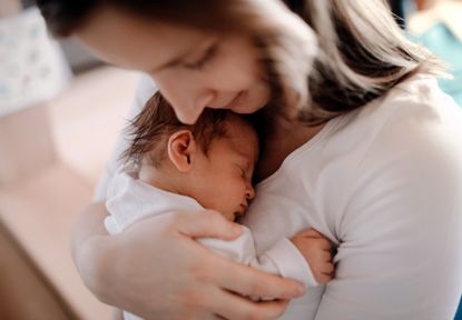 Woman holding a young baby after having stitches after birth