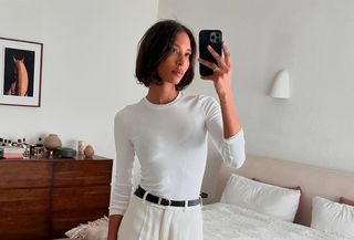 @tylynnnguyen wearing a white three-quarter-sleeve white tee with white trousers and a black belt.