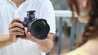 Closeup of Nikon ZR held in a person's hands being used to video someone