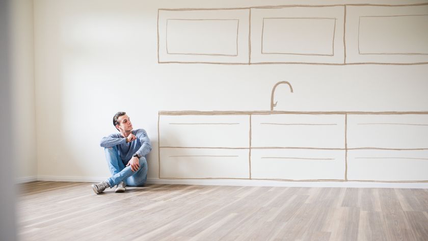 man sat on floor with outline of kitchen cabinets drawn on wall